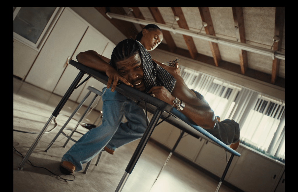 Smino se fait tatouer par un élève dans sa vidéo réfléchissante "Dear Fren"